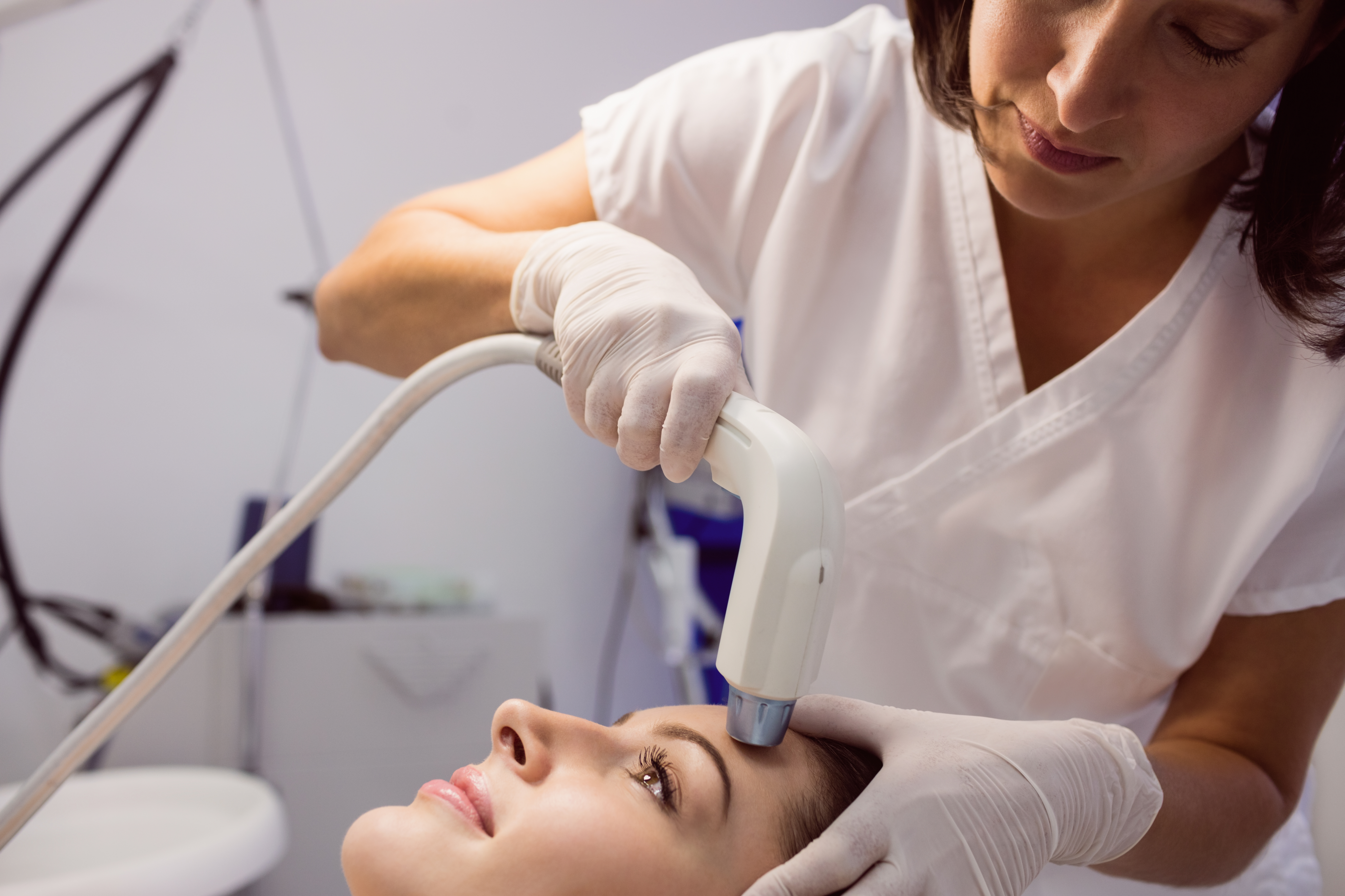 Doctor giving cosmetic treatment to female patient at clinic